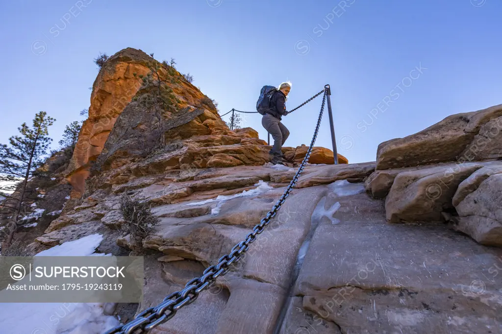 United States, Utah, Zion National Park, Low angle view of senior female hiker on Angels Landing trail in Zion National Park