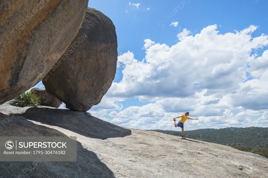 Australia, Queensland, Girraween National Park, Man exercising next to large boulder