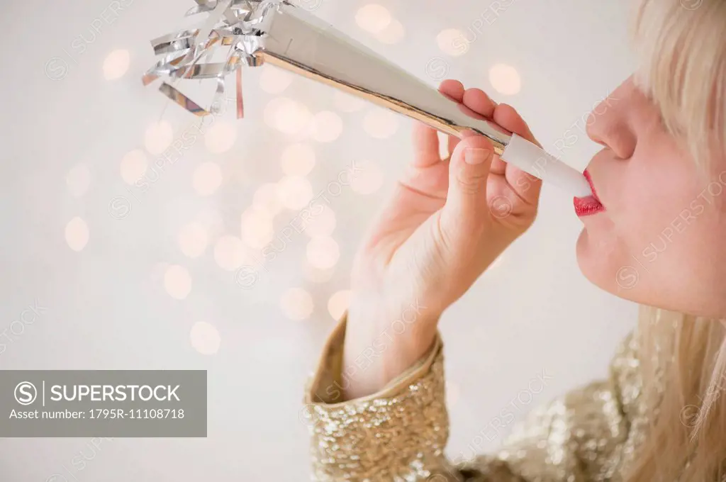 Studio Shot of woman blowing noicemaker at party