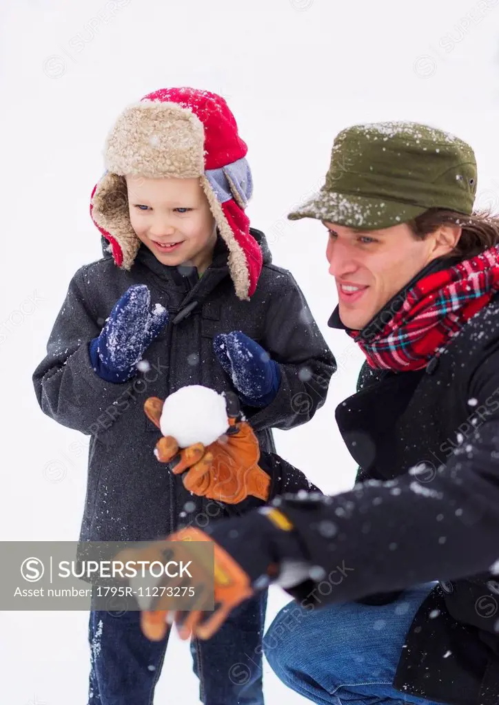 Father and son (6-7) playing with snowball