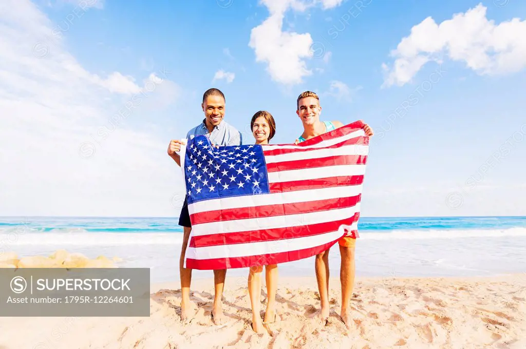 Young people holding American flag on beach