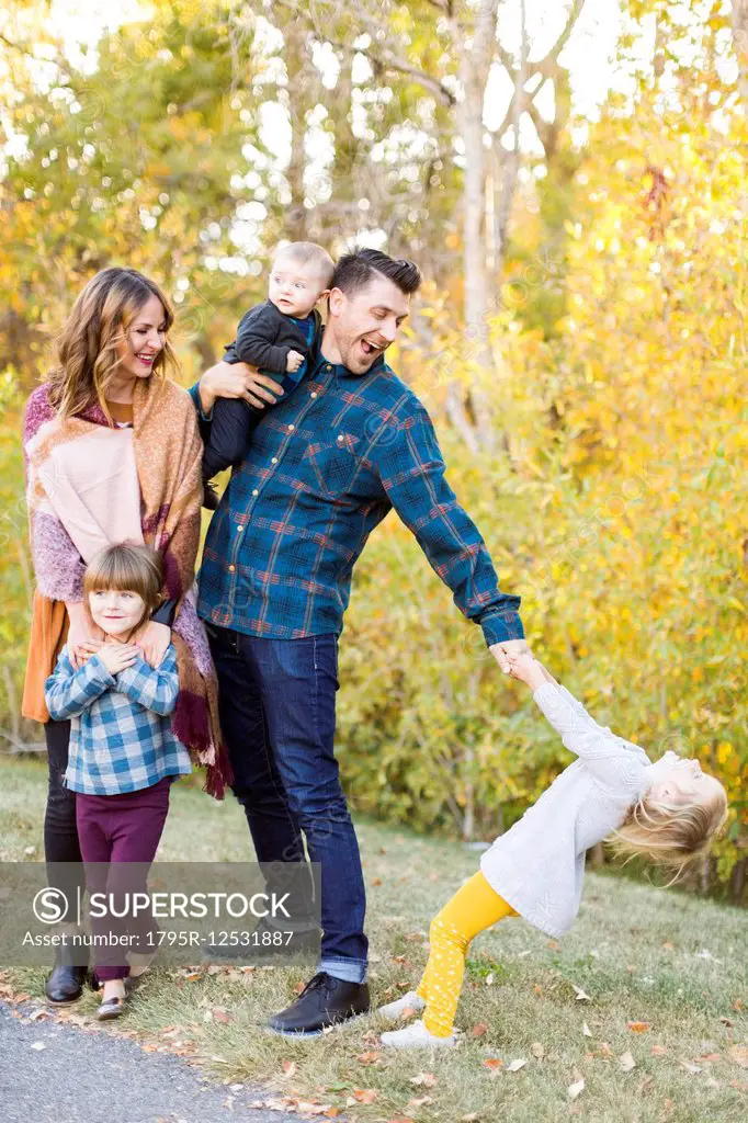 Happy family with tree children (6-11 months, 2-3, 4-5) in park