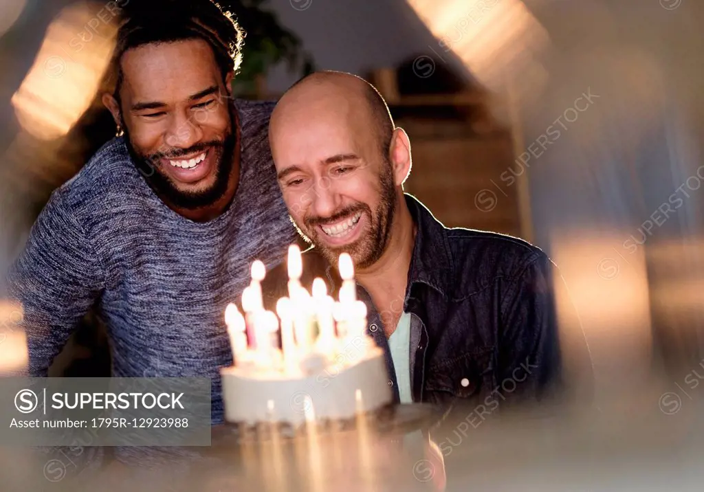 Smiley homosexual couple looking at birthday cake