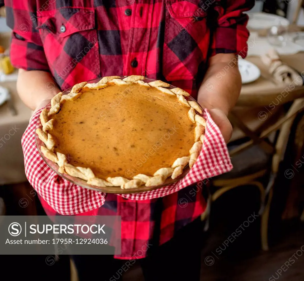 Woman holding baked pumpkin pie for Thanksgiving