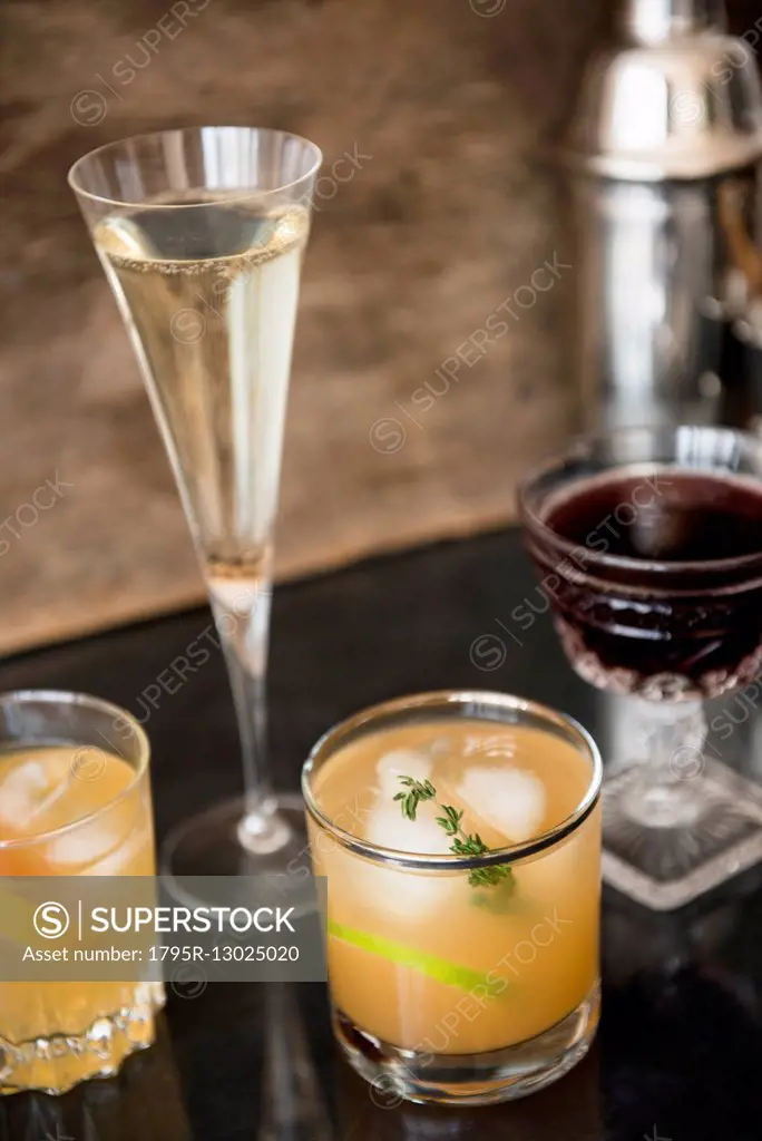 Cocktails and cocktail shaker on table