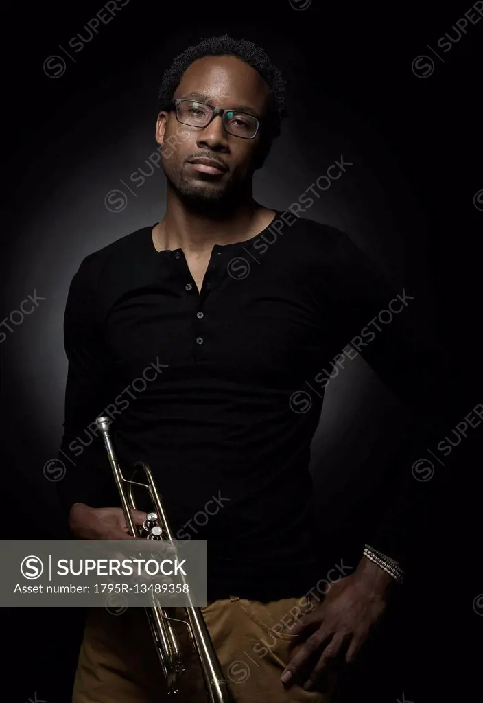 Studio portrait of mid adult man holding trumpet