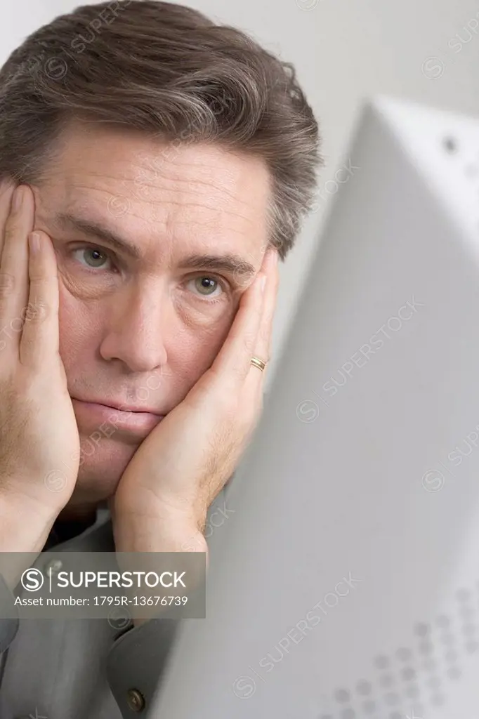 Discouraged man looking at computer monitor