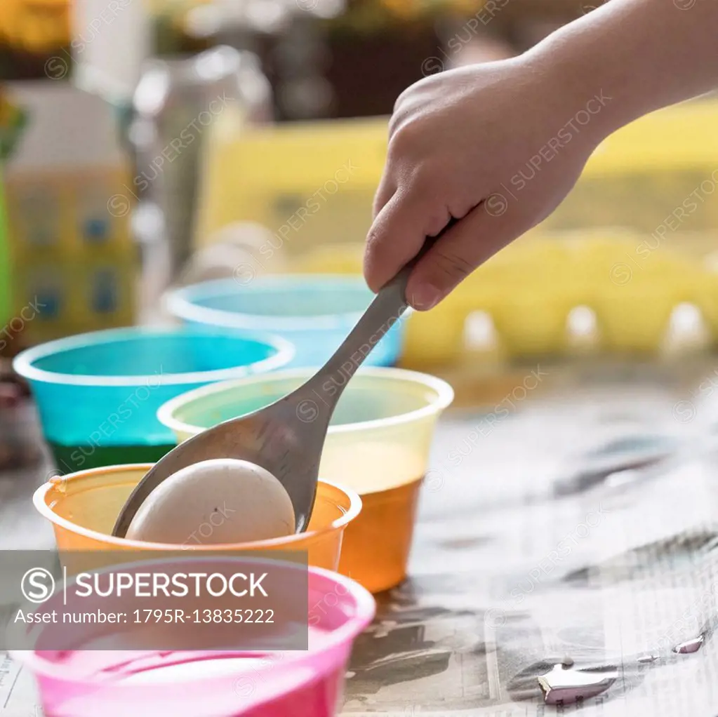 Girl (4-5) making colored Easter eggs