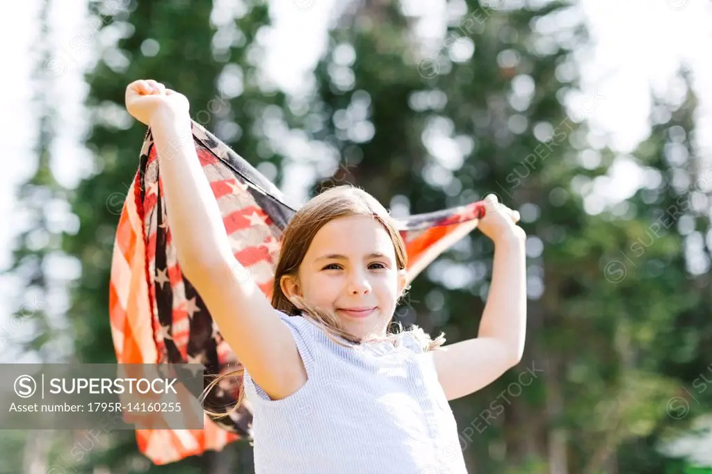 Girl (8-9) holding us flag in forest