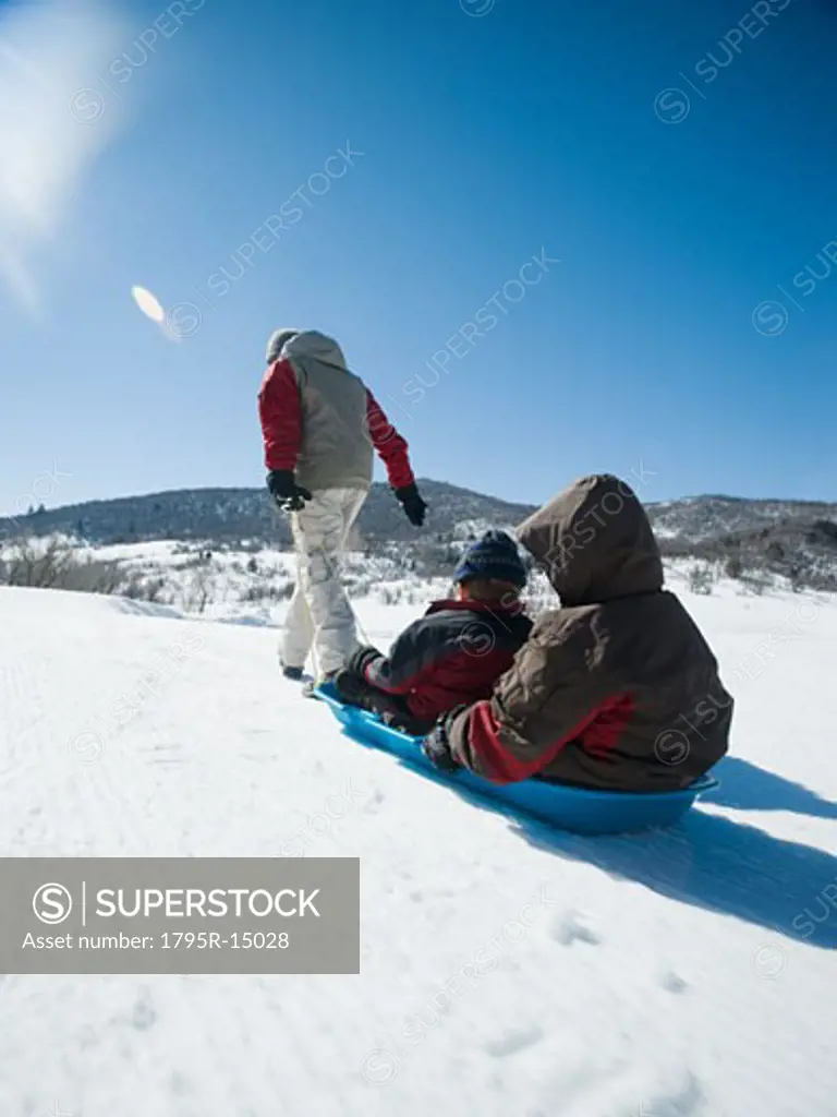 Father pulling children on sled