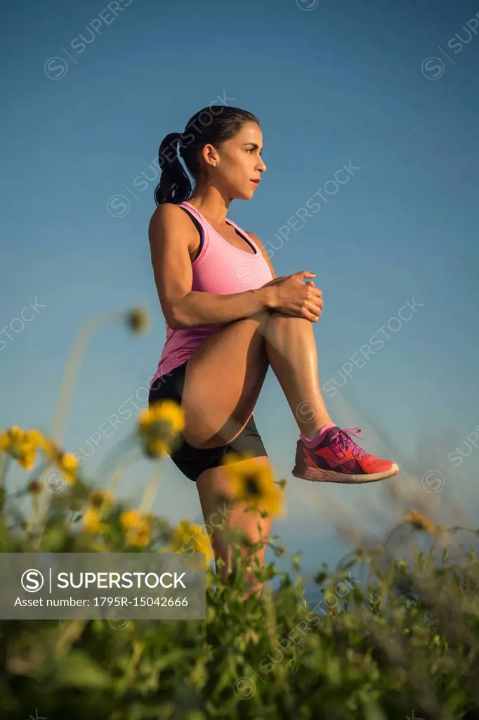 Woman stretching against blue sky