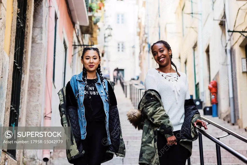 Portugal, Lisbon, Two smiling young women walking outdoors