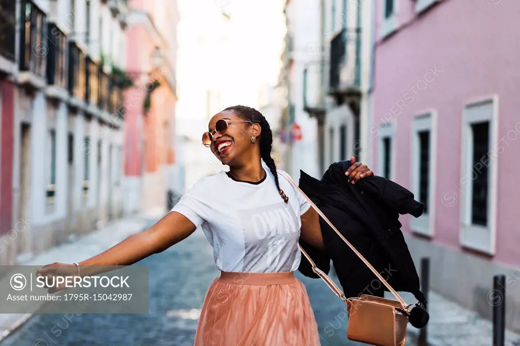 Portugal, Lisbon, Smiling young woman dancing in old town