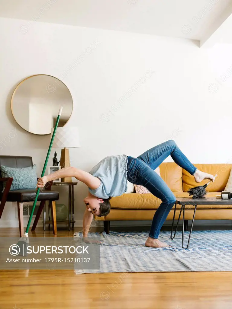 Woman bending over backwards sweeping and dusting - SuperStock