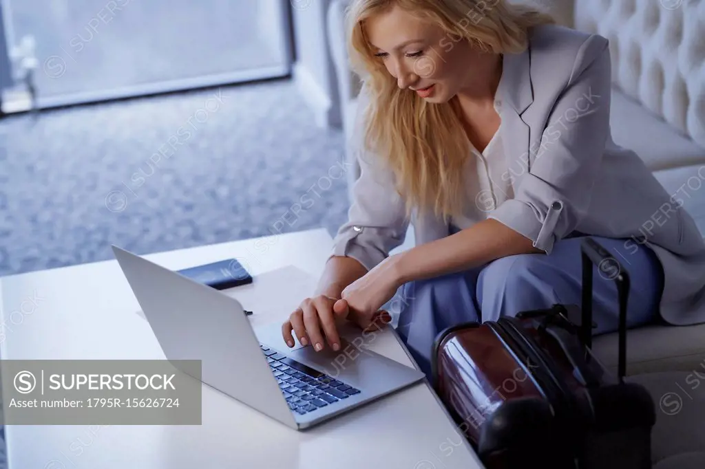 Businesswoman working on laptop in airport lounge