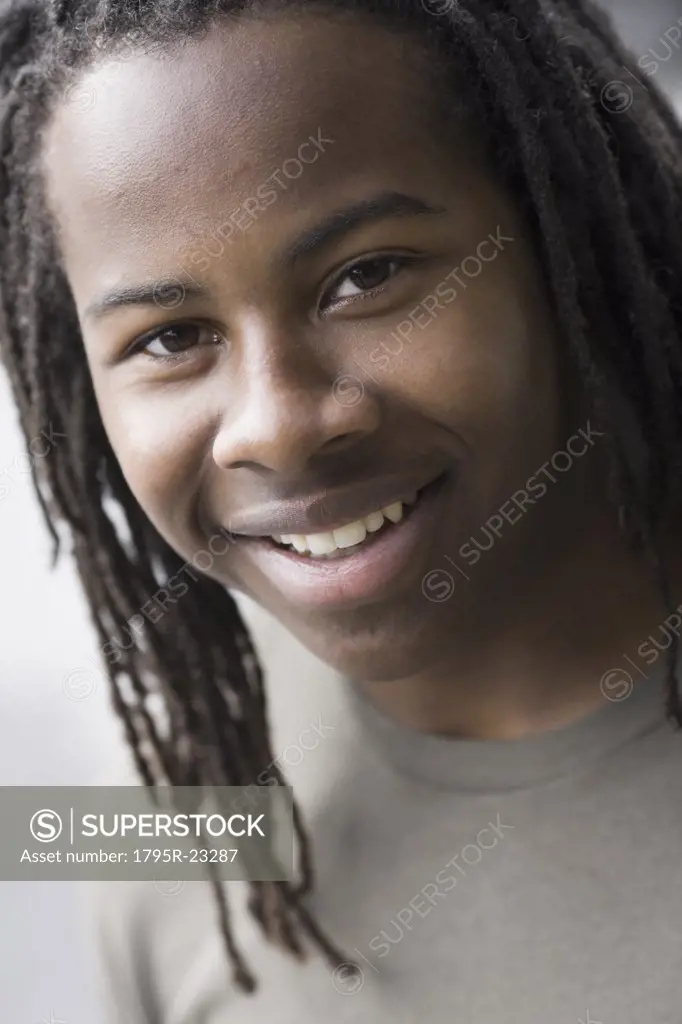 Portrait of teenage boy (16-17) with dreadlocks, smiling