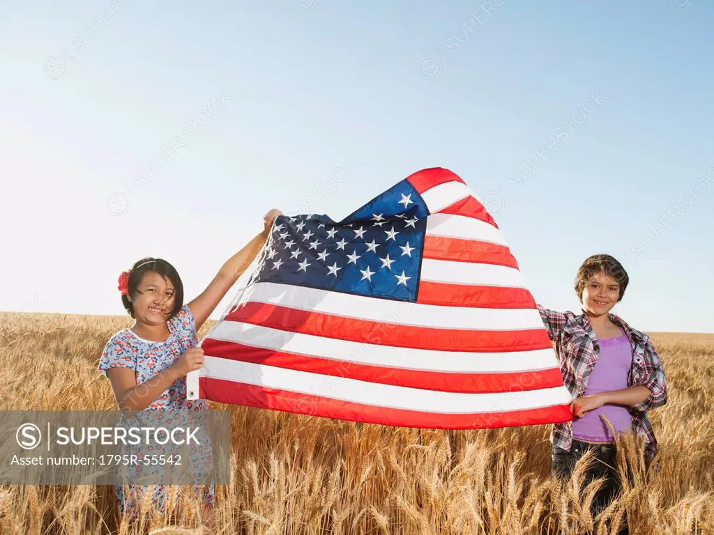 Girls 10_11, 12_13 holding american flag in wheat field