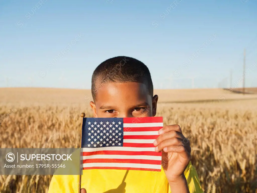 Boy 8_9 holding a small American flag in wheat field