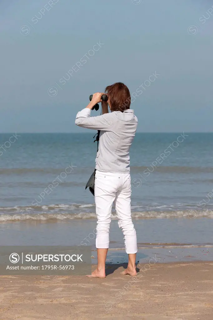 Woman on beach looking through binoculars