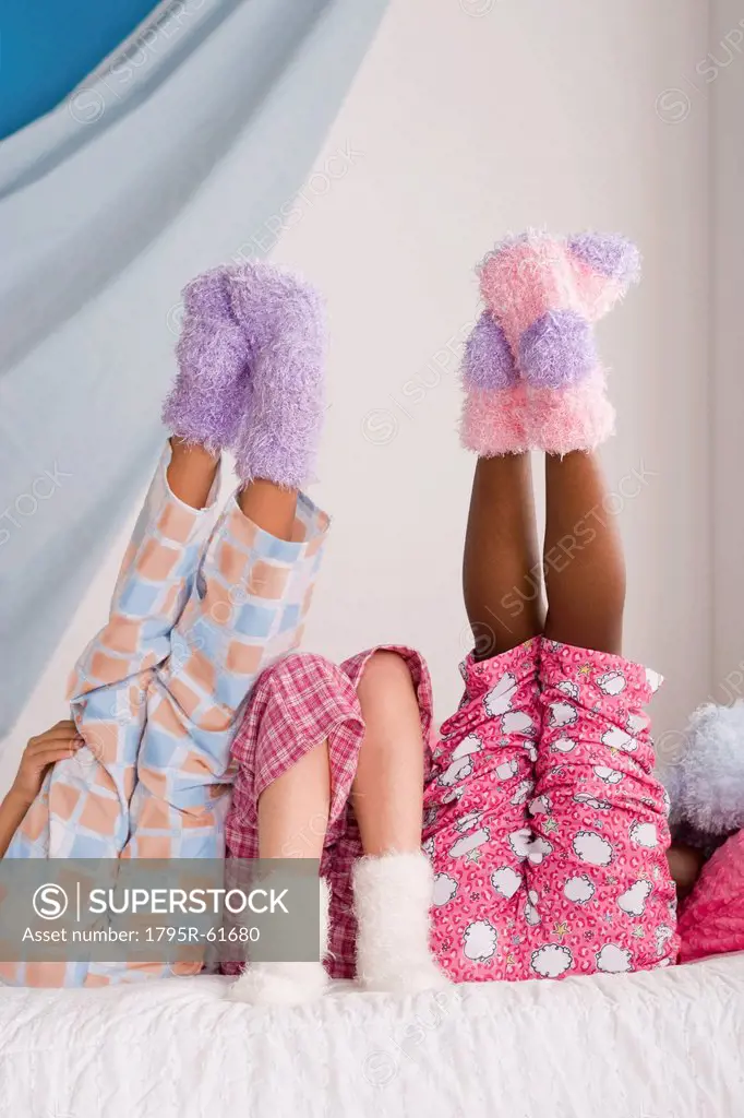 Close op of legs of three girls 10_11 lying on bed with feet up