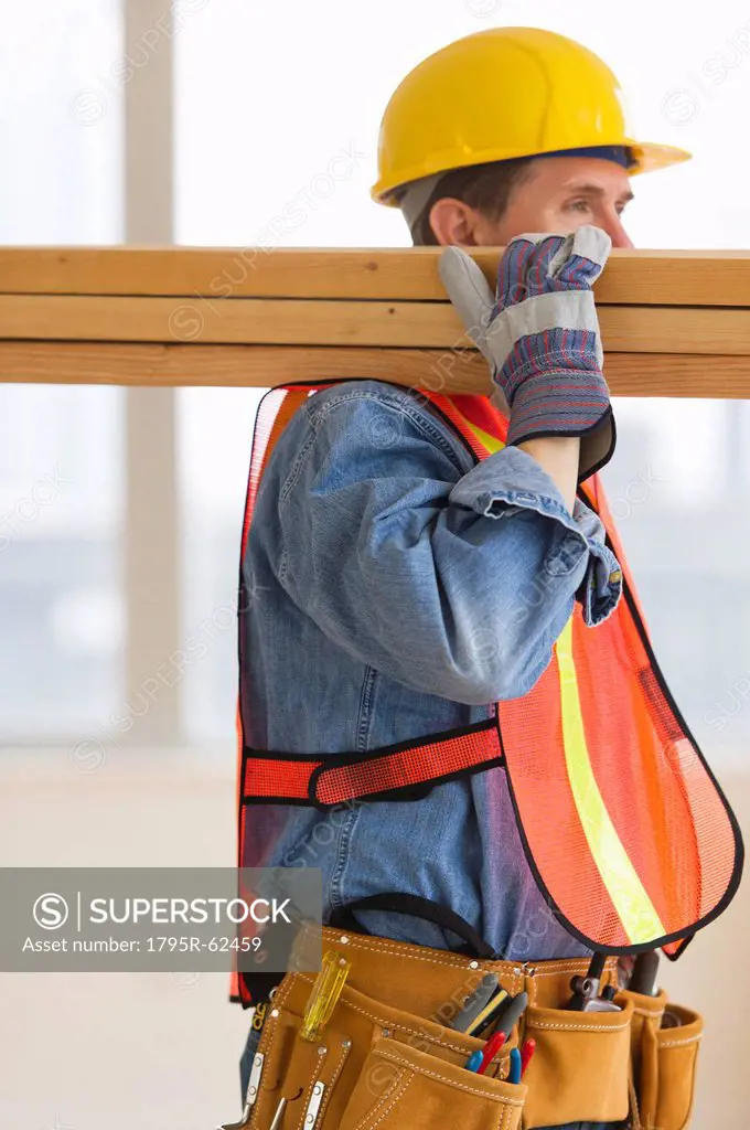 Construction worker carrying planks