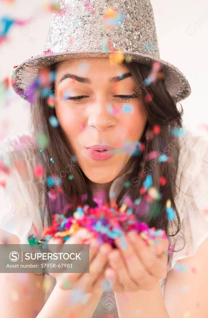 Portrait of young woman blowing confetti