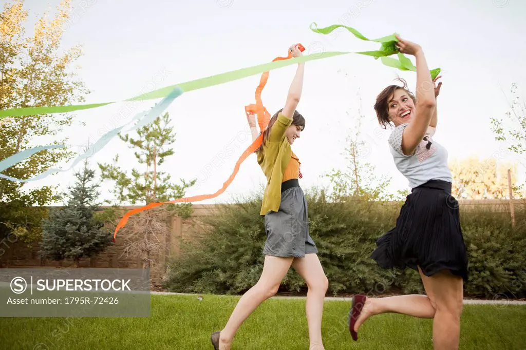 Two happy female friends playing in domestic garden