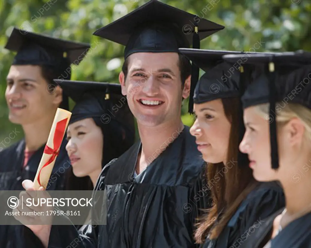 Male college graduate holding diploma - SuperStock