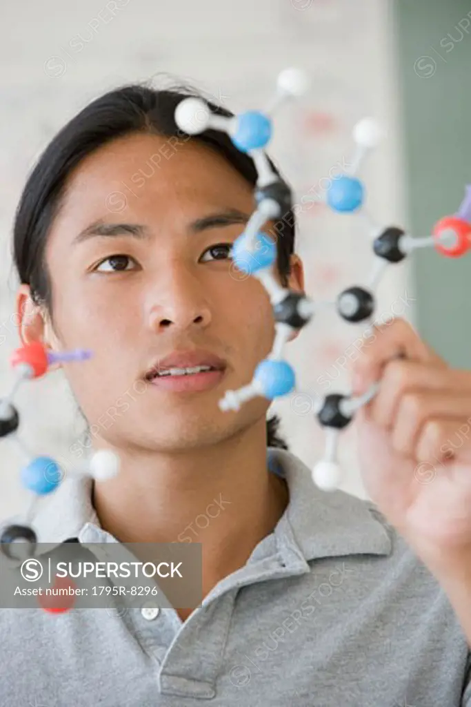 Asian male college student looking at molecule model