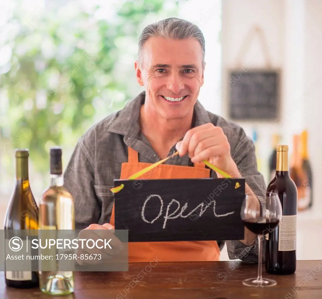 Portrait of wine store owner holding open sign