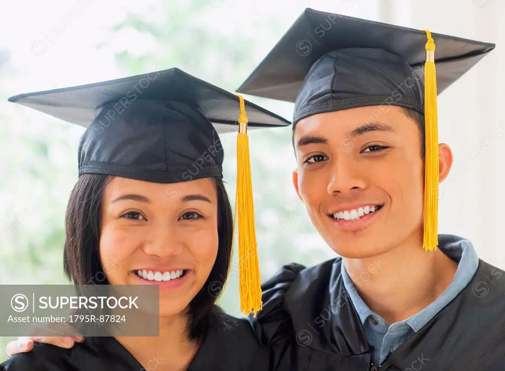 Portrait of young woman and young man wearing graduation gown