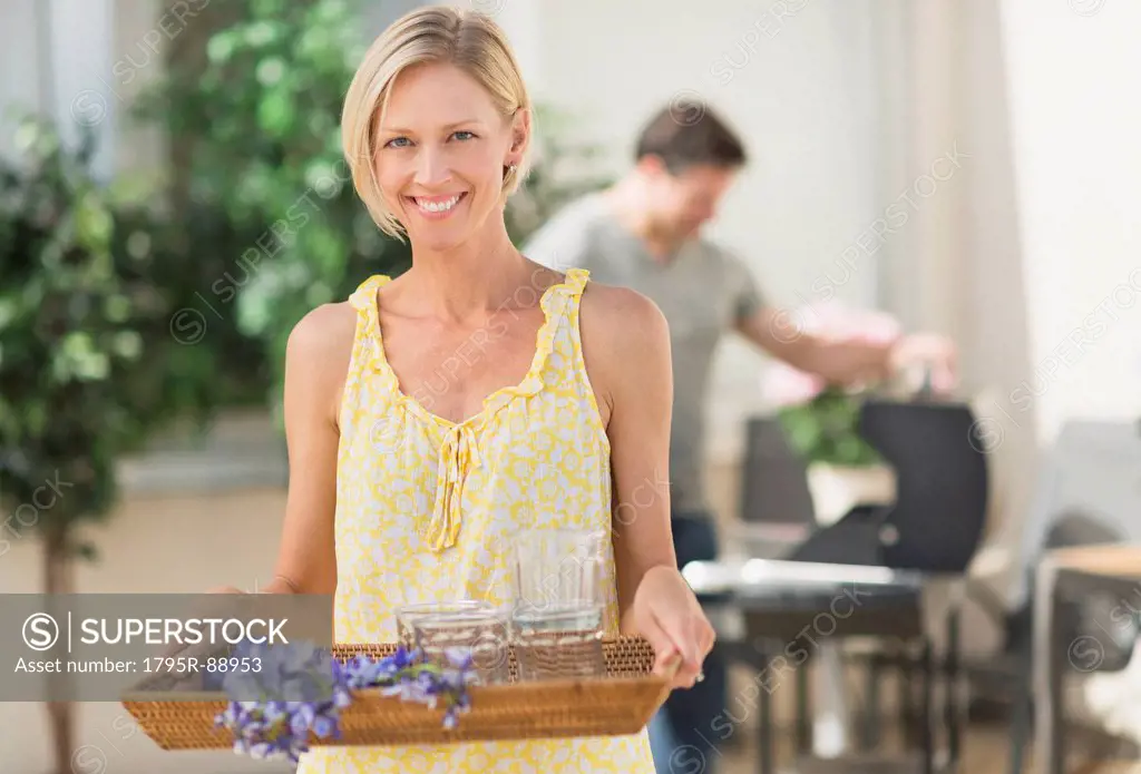 Woman carrying tray with crockery and flowers