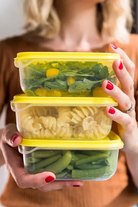 Woman holding stack of food in plastic containers