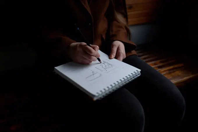 Woman drawing in note pad on train