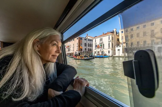 Woman looking out of boat window on Grand Canal, Venice, Italy