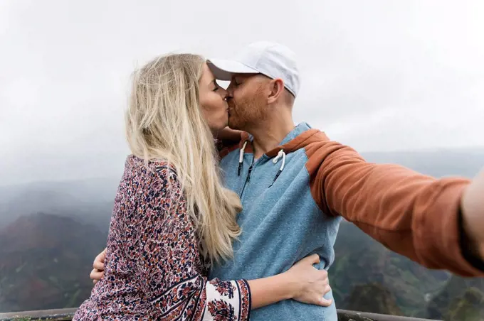 Mid adult couple taking selfie while kissing