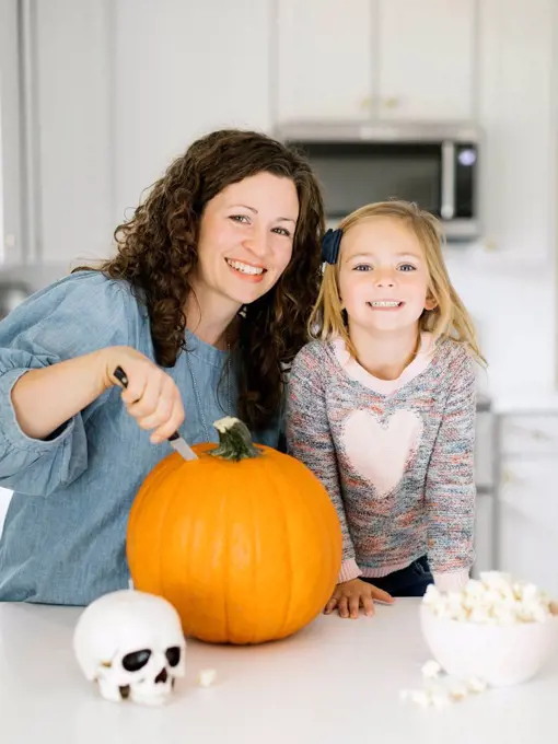 Mother and daughter carving pumpkin for Halloween