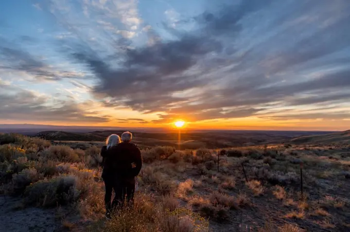 Couple in field at sunset at Boise Foothills in Boise, Idaho, USA