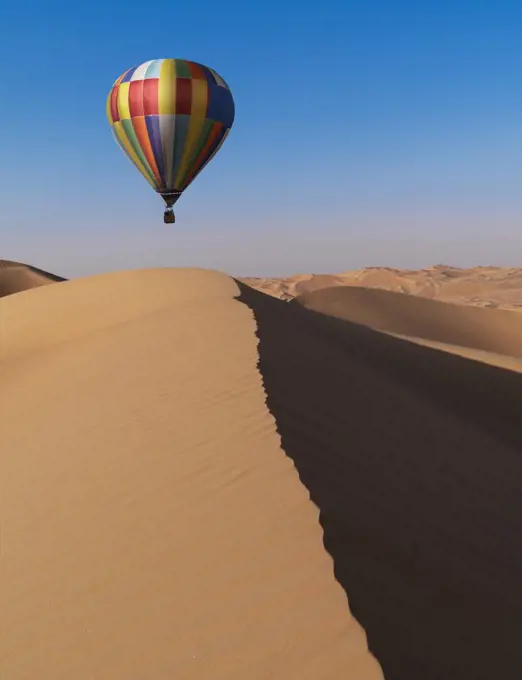 Dubai, United Arab Emirates, Colorful hot air balloon flying over sand dunes