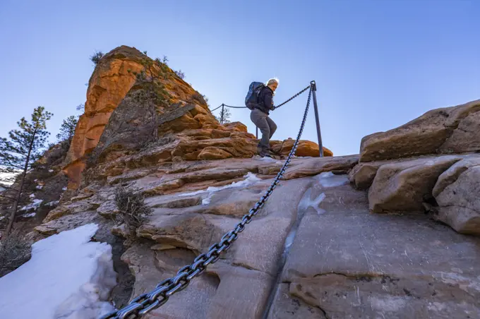 United States, Utah, Zion National Park, Low angle view of senior female hiker on Angels Landing trail in Zion National Park