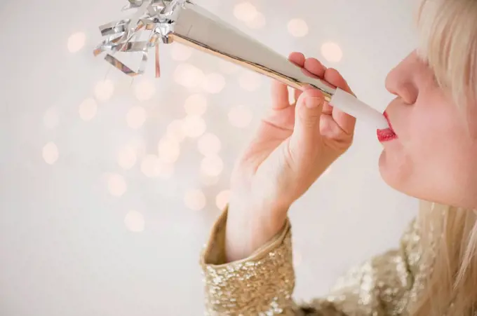 Studio Shot of woman blowing noicemaker at party