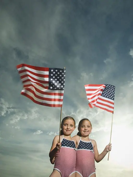 Two young sisters holding American flags