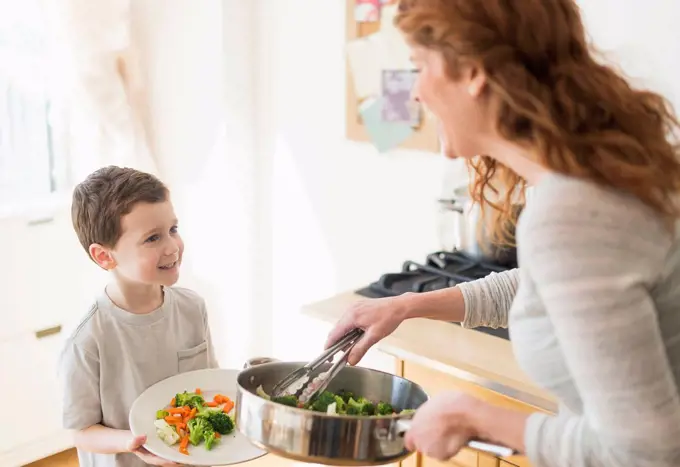 Mother and son (6-7) serving healthy dinner