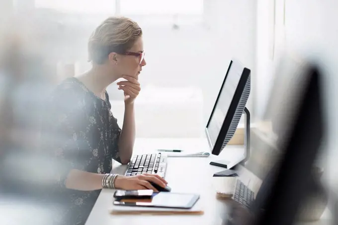 Side view of business woman working on desktop pc in office