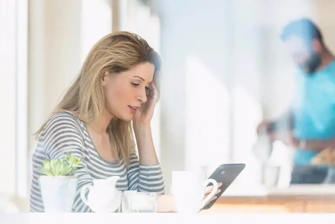 Young woman using tablet and man in background