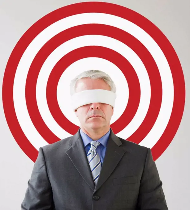 Blindfolded man standing in front of bull´s eye