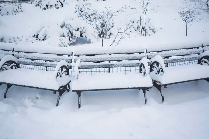 USA, New York City, Manhattan, Benches in Central Park covered with snow