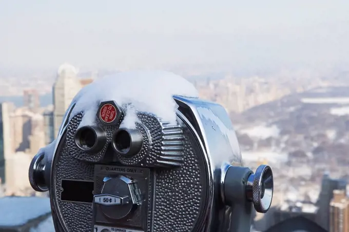 USA, New York City, Coin operated binoculars covered with snow, Central Park in background