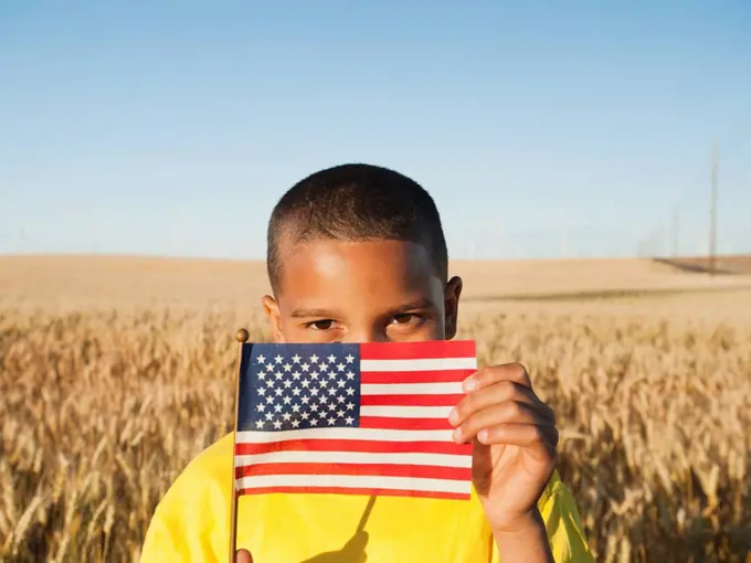 Boy 8_9 holding a small American flag in wheat field