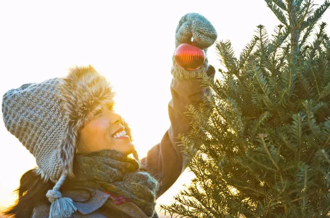 Smiling woman decorating Christmas tree